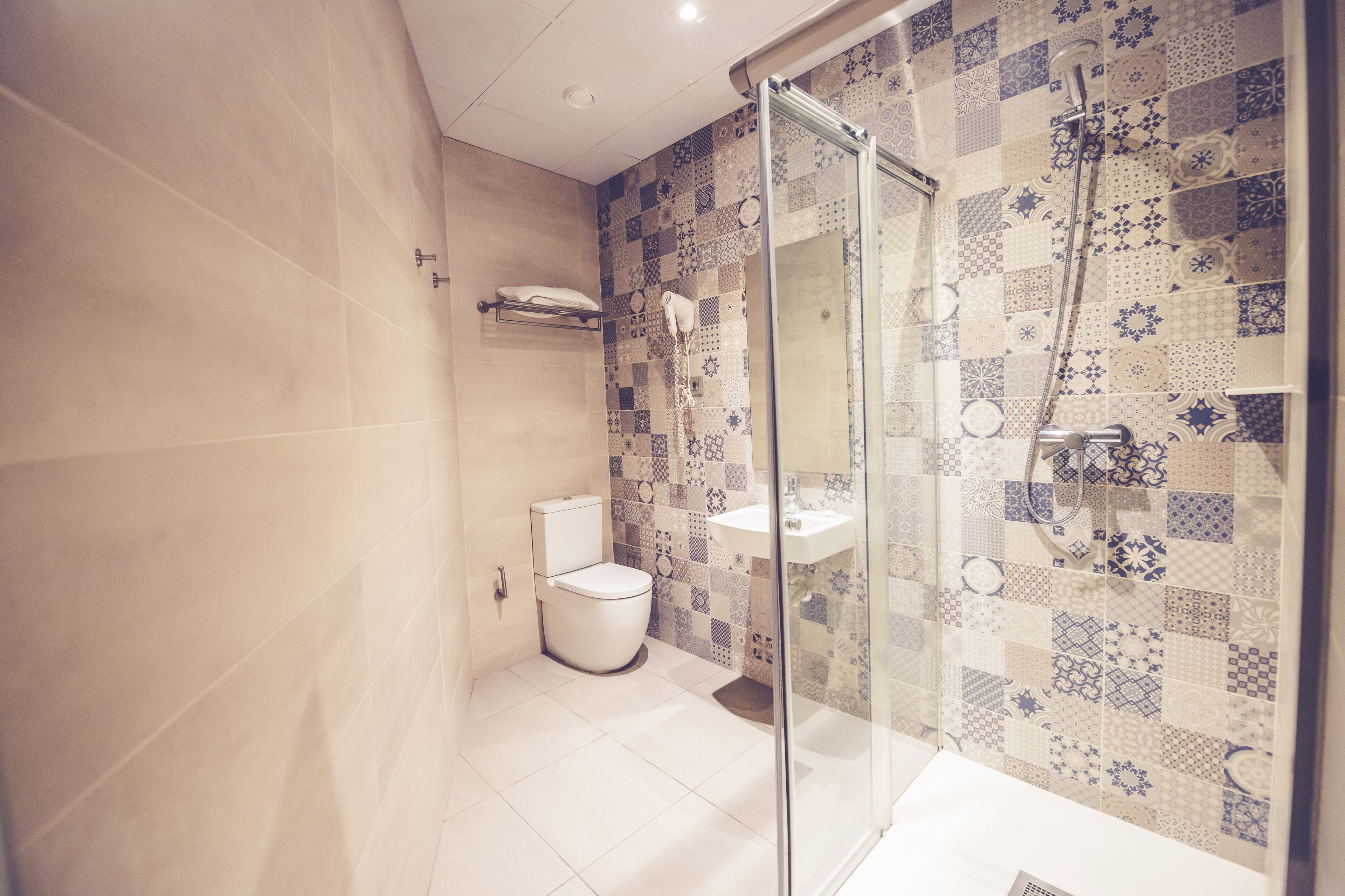 A modern bathroom with a glass shower enclosure, a toilet, and a sink.