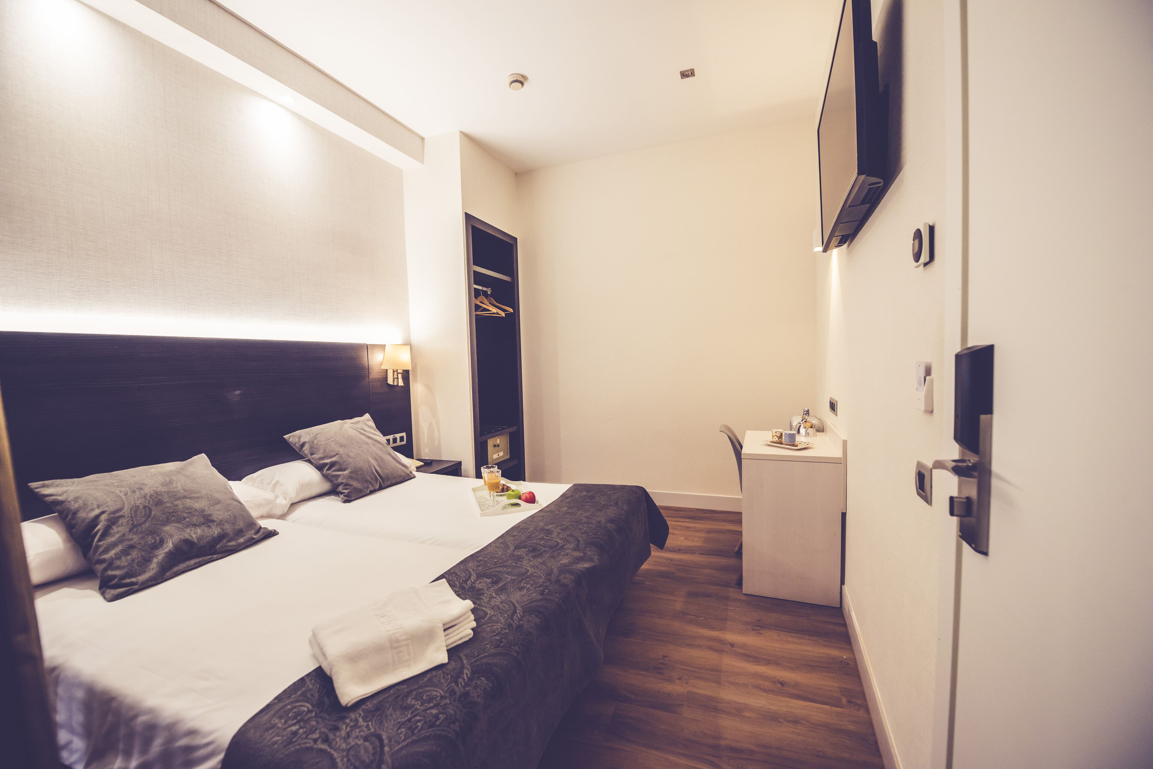 Une chambre d’hôtel comprenant un lit, une table de chevet et un bureau avec une chaise.