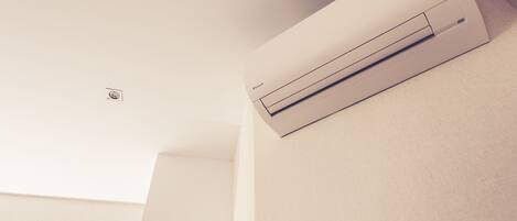 A wall-mounted air conditioning unit in a room with a plain ceiling and minimalistic design.