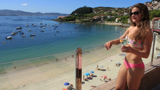 Un balcón con vista a una playa y barcos.