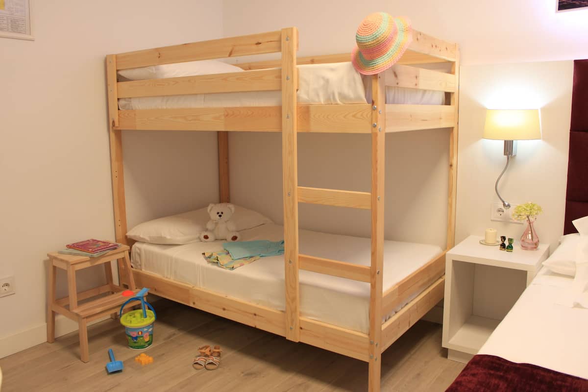 Habitación con literas, una mesita, una lámpara y un osito de peluche.