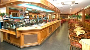 Un restaurante con mostrador de madera, mesas y sillas.
