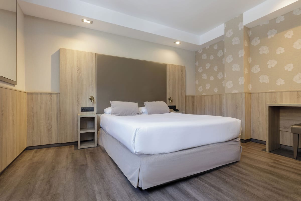 A modern bedroom with a large bed, built-in wardrobe, and a small desk.