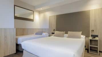 Una habitación de hotel moderna con dos camas individuales, un espejo grande y un armario de madera.