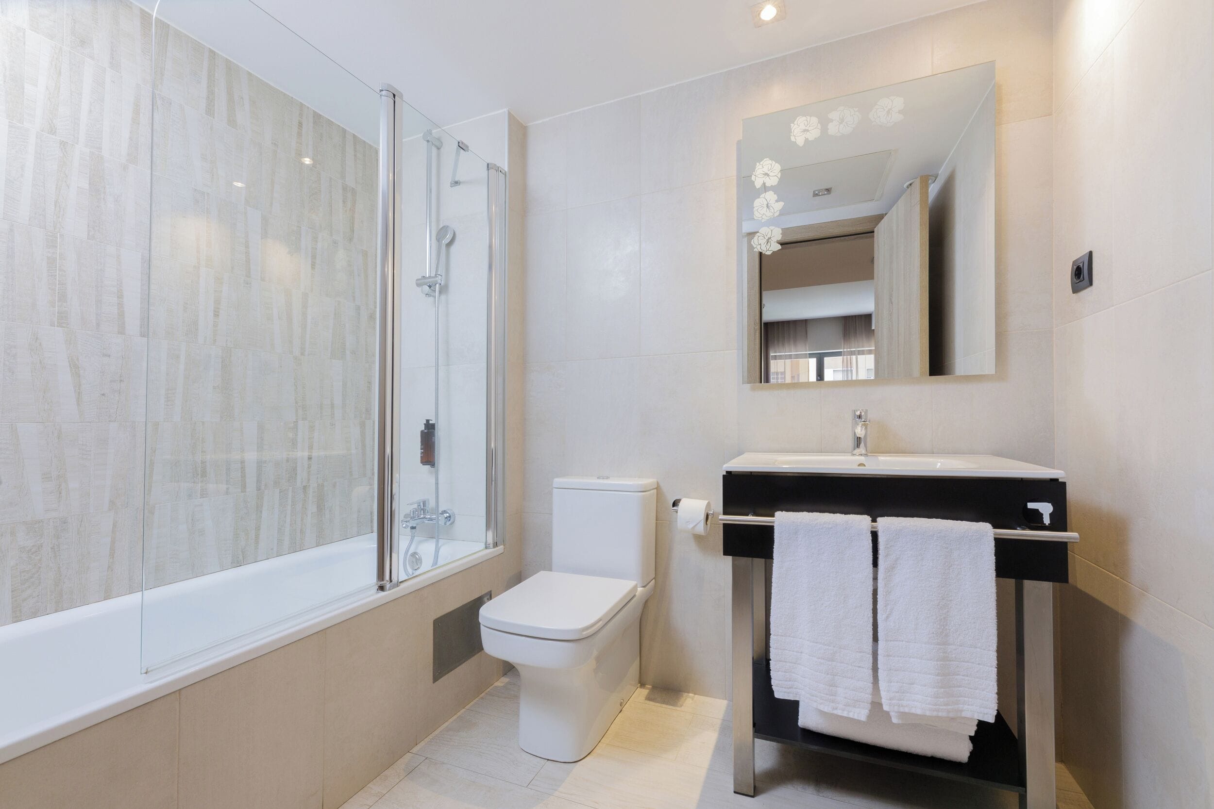 Een moderne badkamer met een douchecabine van glas, een toilet en een wastafel met een spiegel erboven.