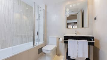 Een moderne badkamer met een douchecabine van glas, een toilet en een wastafel met een spiegel erboven.