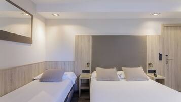 Habitación de hotel con dos camas, un espejo grande y un armario de madera.