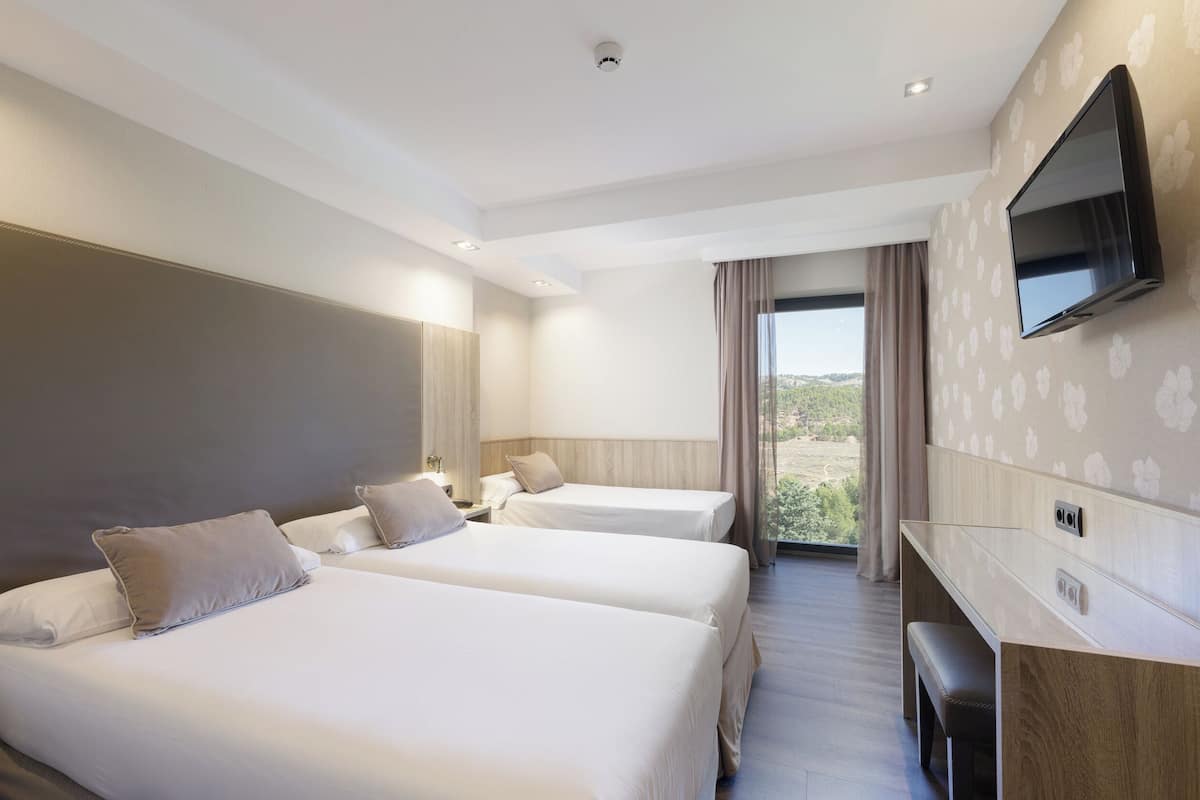 A hotel room with two beds, a TV, and a desk.