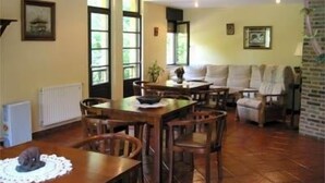 A dining area with a wooden table and chairs, a sofa, and a radiator. - Hotel Benzúa (Llanes)