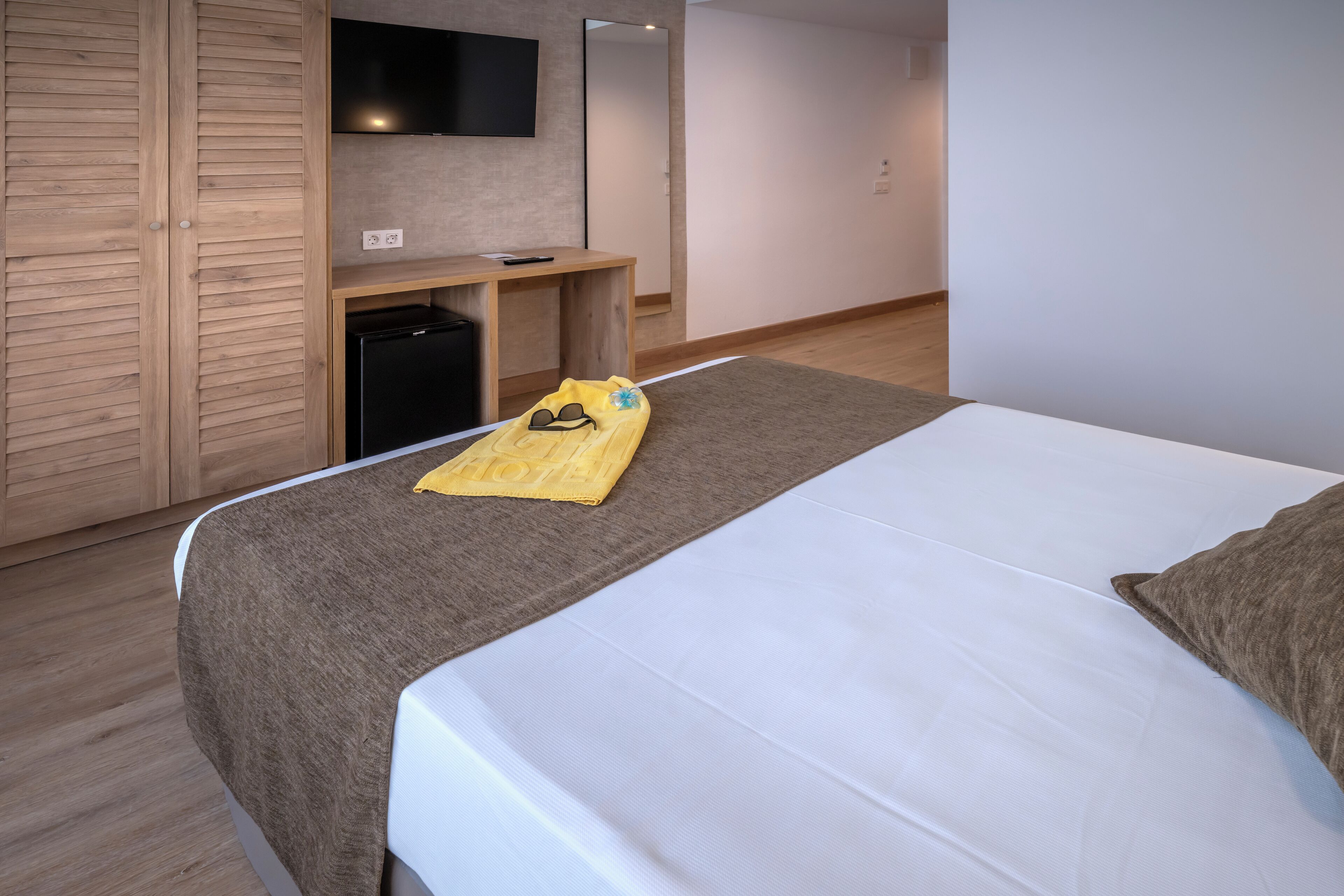 Una habitación de hotel con cama, escritorio, televisión y armario.