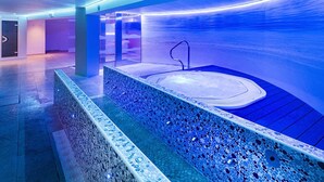 Una piscina interior moderna amb vora de mosaic i una zona central de banyera d'hidromassatge.