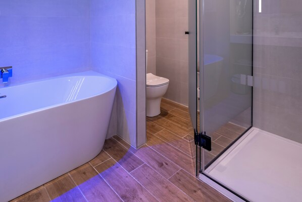 A modern bathroom with a freestanding bathtub, a toilet, and a glass-enclosed shower area.