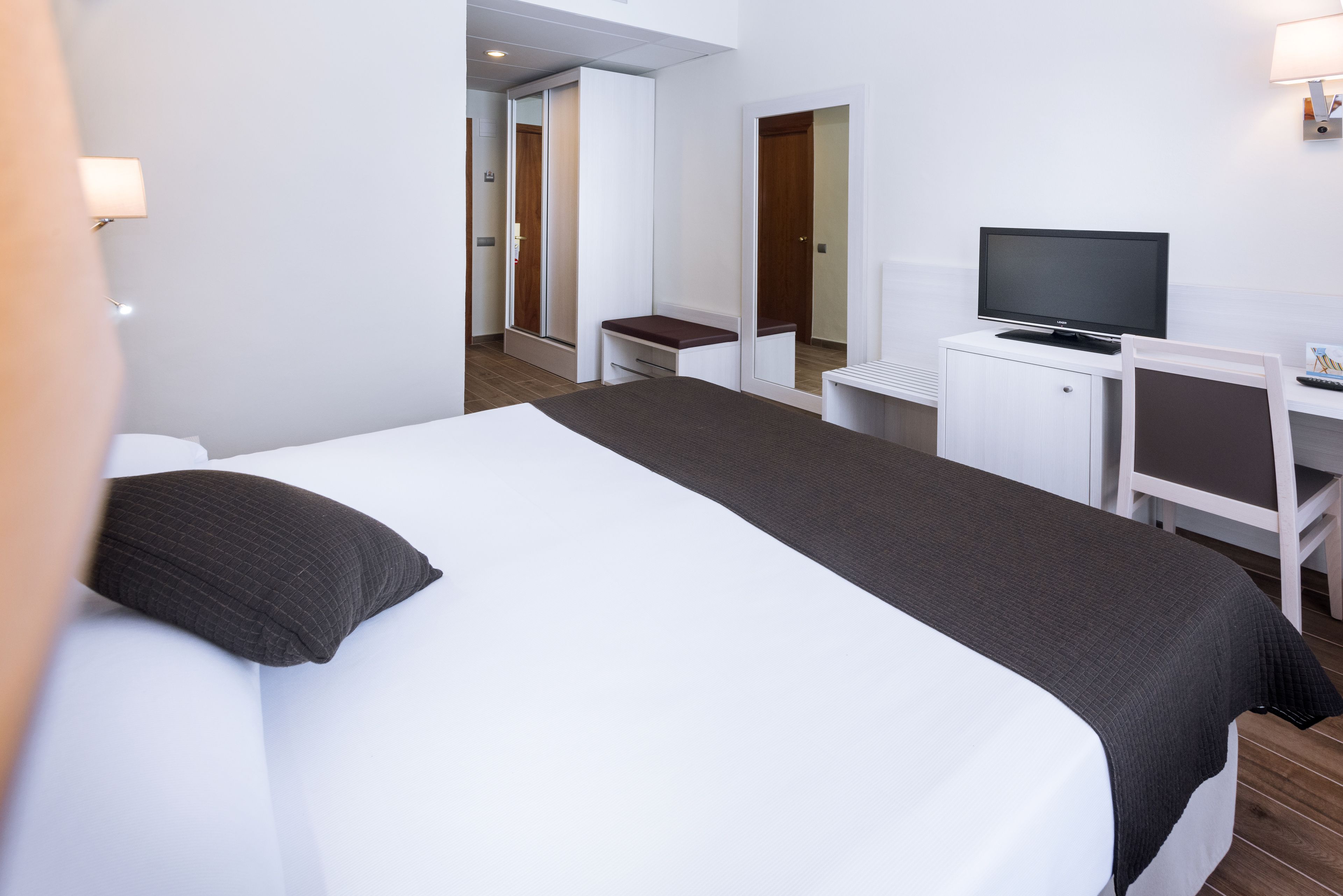 Ein Hotelzimmer mit einem Bett, einem Schreibtisch, einem Fernseher und einem Kleiderschrank.