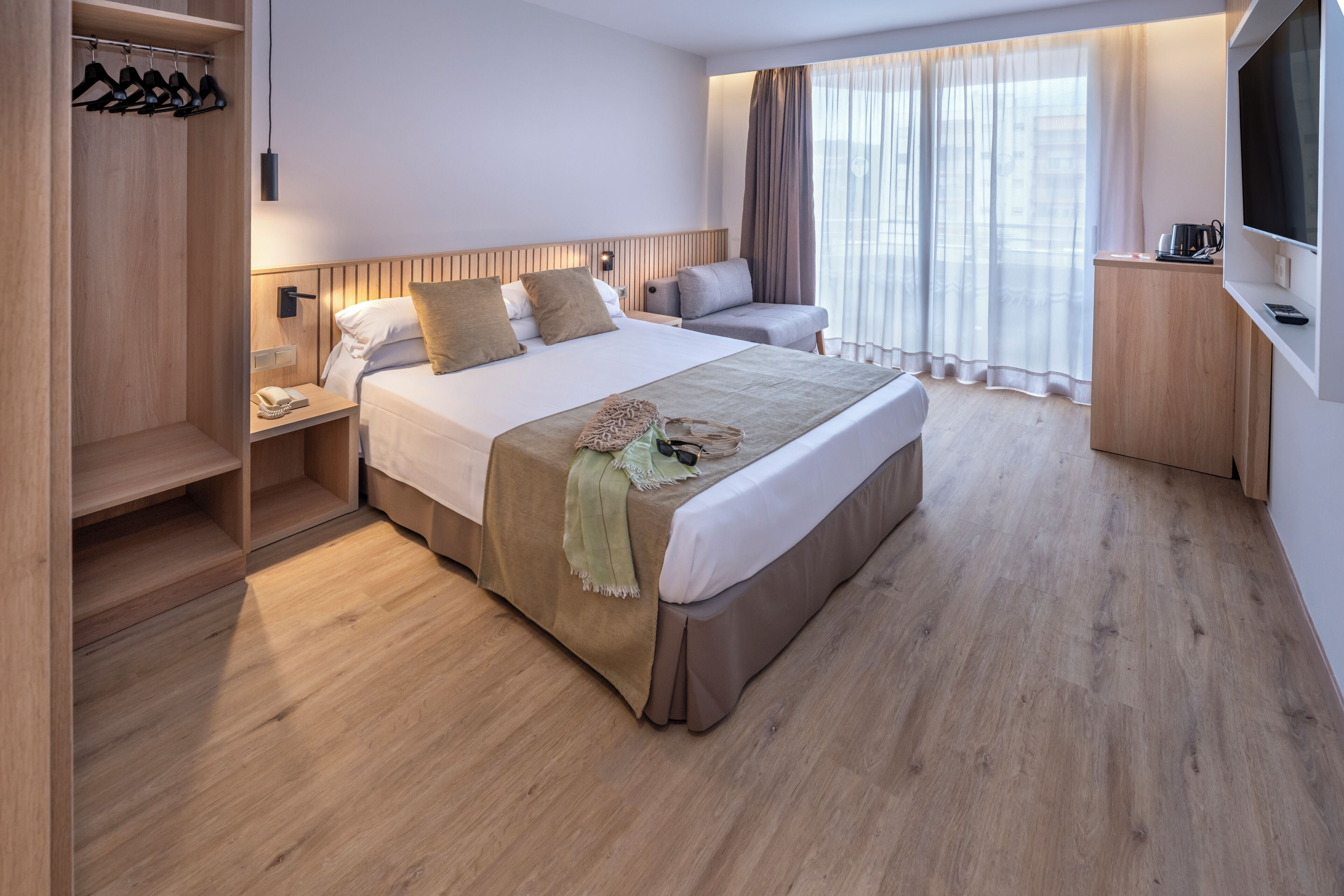 Una habitación de hotel con una cama grande, un escritorio, un televisor y un armario.