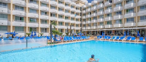 Una piscina techada, una piscina al aire libre, sombrillas