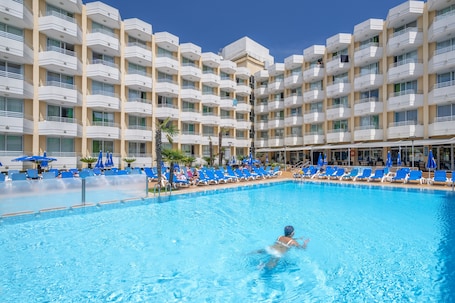 Una piscina techada, una piscina al aire libre, sombrillas