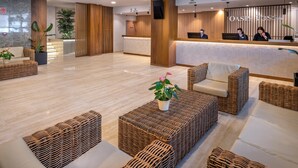 A modern hotel lobby with a reception desk, check-in counters, and comfortable seating areas. - Hotel GHT Oasis Tossa & Spa (Tossa de Mar)