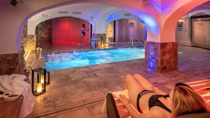 Ein Wellnessbereich mit Whirlpool, eine Person steht am Becken, eine weitere Person entspannt auf einer Liege.
