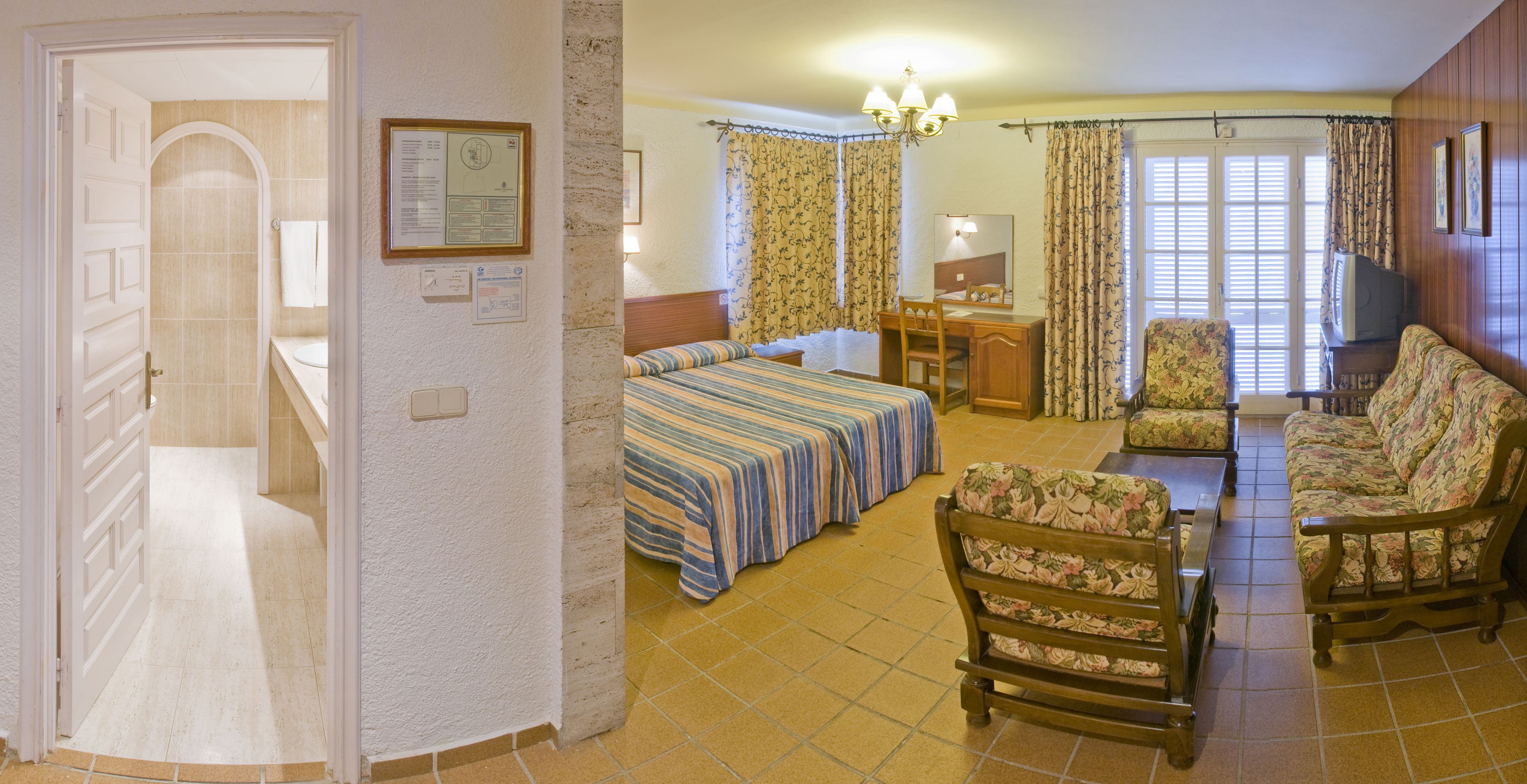 A hotel room with a bed, a desk, a chair, and a sofa.
