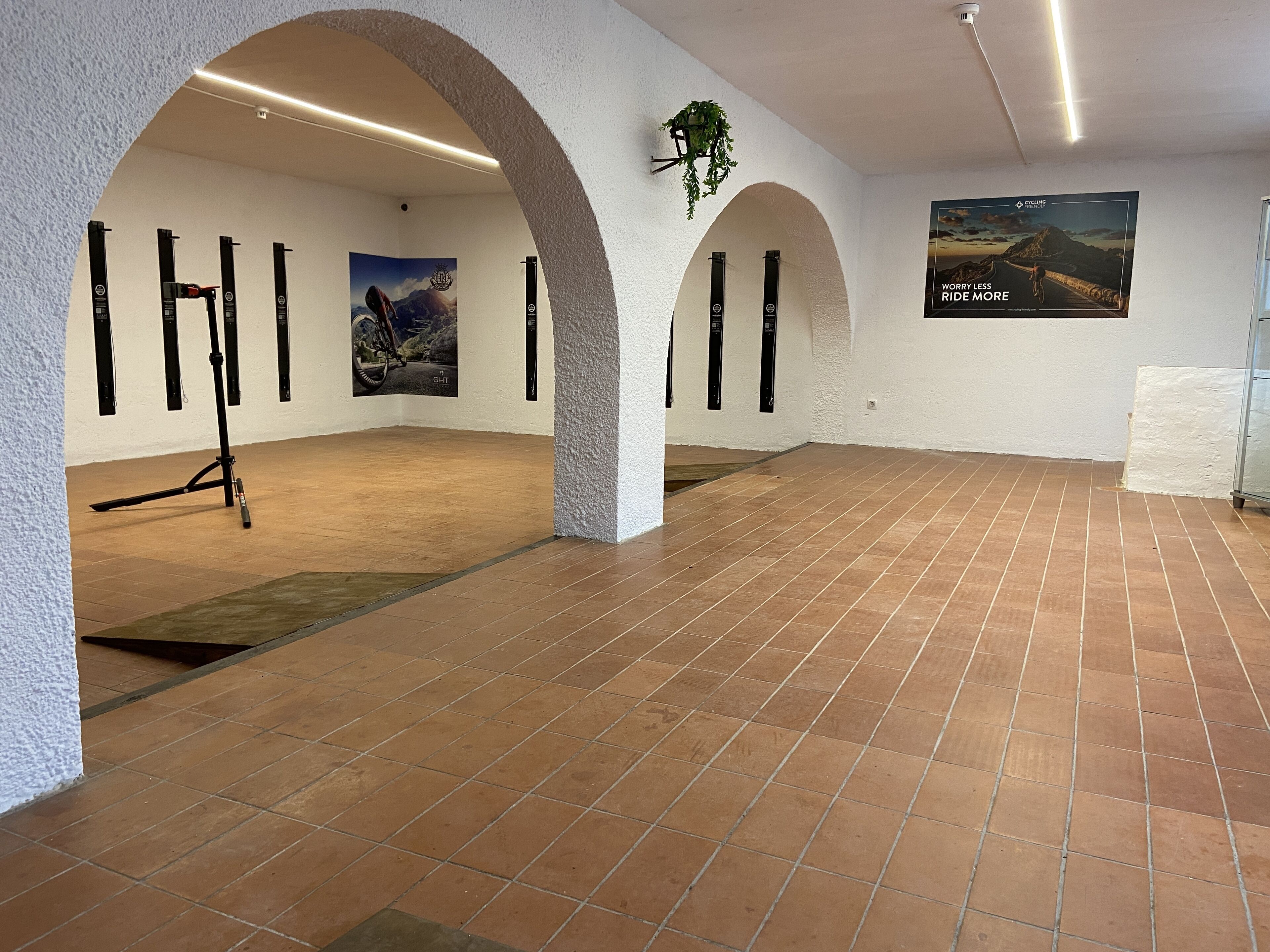 A spacious indoor area with tiled flooring, arched alcoves, and wall-mounted posters.
