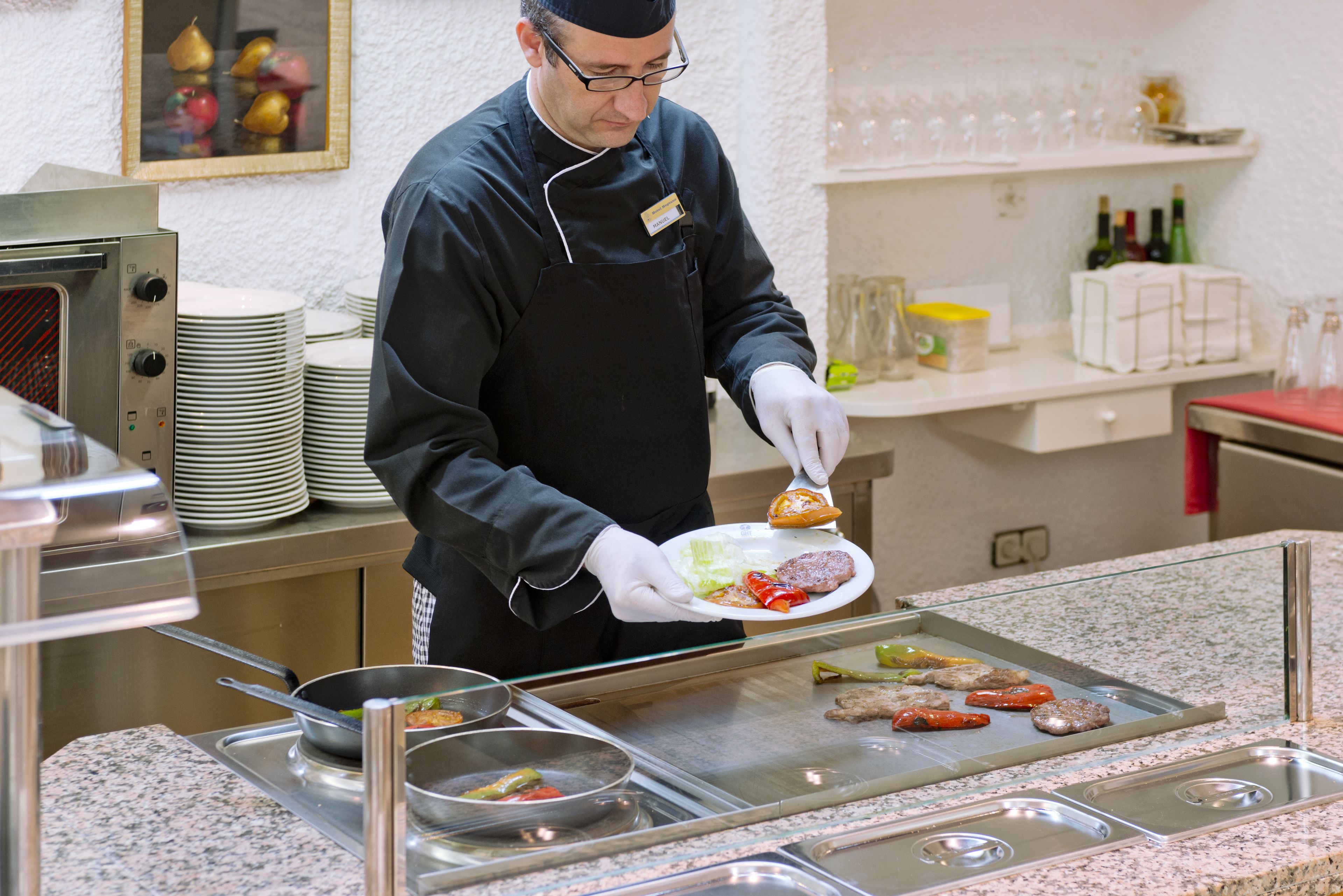 Una persona con uniforme sirviendo comida en un bufé.