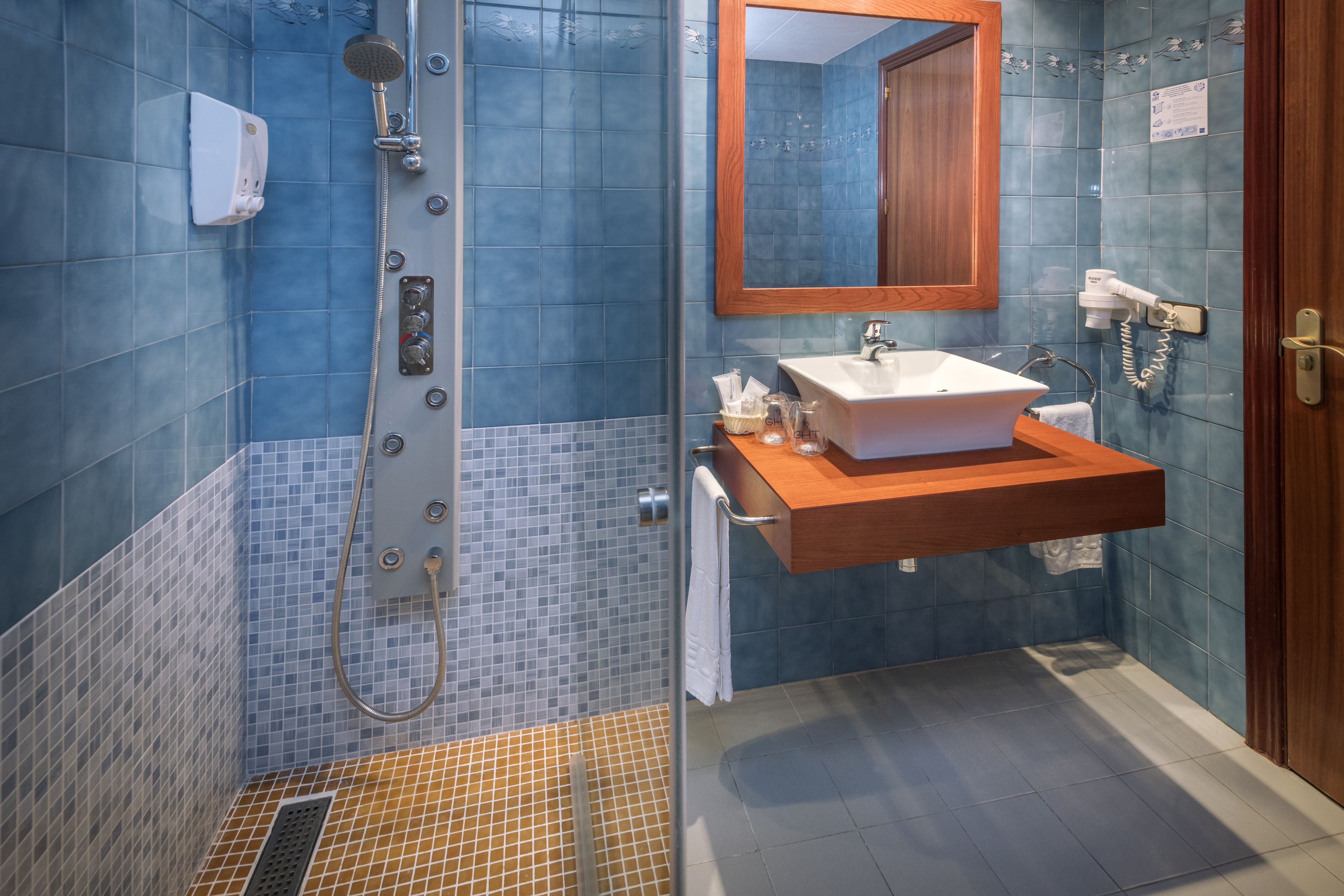 A bathroom with a shower, sink, and mirror.