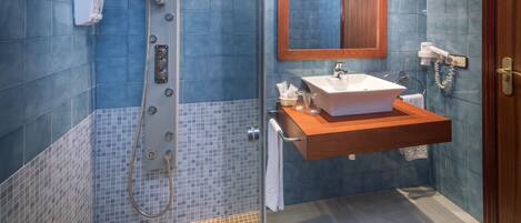 A bathroom with a shower, sink, and mirror.