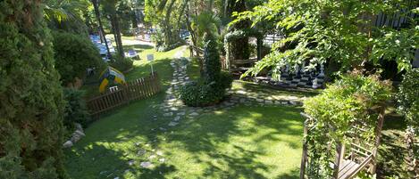 A well-maintained garden with a stone pathway, lush greenery, and a wooden bench.