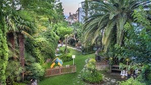 Ein üppiger Garten mit Palmen, einem Holzzaun und einem kleinen Spielbereich.