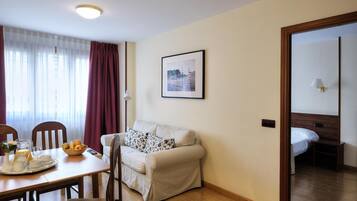Een hotelkamer met een eethoek, een bank, een bed en een lijst met een foto aan de muur.