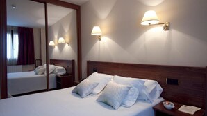 A hotel room with a large bed, two bedside lamps, a nightstand, and a mirror. - Palacio Arias & Hotel y Apartamentos Arias (Navia)