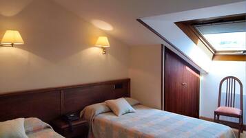 Habitación de hotel con dos camas, un escritorio con teléfono, una silla y un armario.