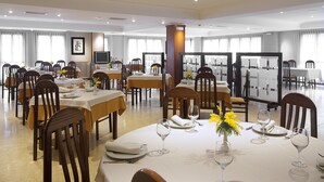 A spacious dining area with multiple tables set for dining, chairs, and a television screen. - Palacio Arias & Hotel y Apartamentos Arias (Navia)