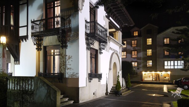 A hotel with a traditional European architectural style, featuring balconies with wrought iron railings, a cobblestone courtyard, and a well-lit entrance. - Palacio Arias & Hotel y Apartamentos Arias (Navia)
