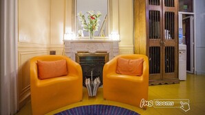 Una habitación con dos sillones anaranjados, una chimenea, un espejo y un aparador.