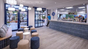 A modern interior with seating areas, a bar, and a view of the outdoor patio. - GHT Balmes, Hotel, Aparthotel & SPLASH (Calella)