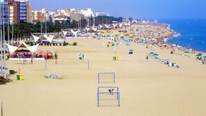 A beach with tents, umbrellas, and beachgoers. - GHT Balmes, Hotel, Aparthotel & SPLASH (Calella)