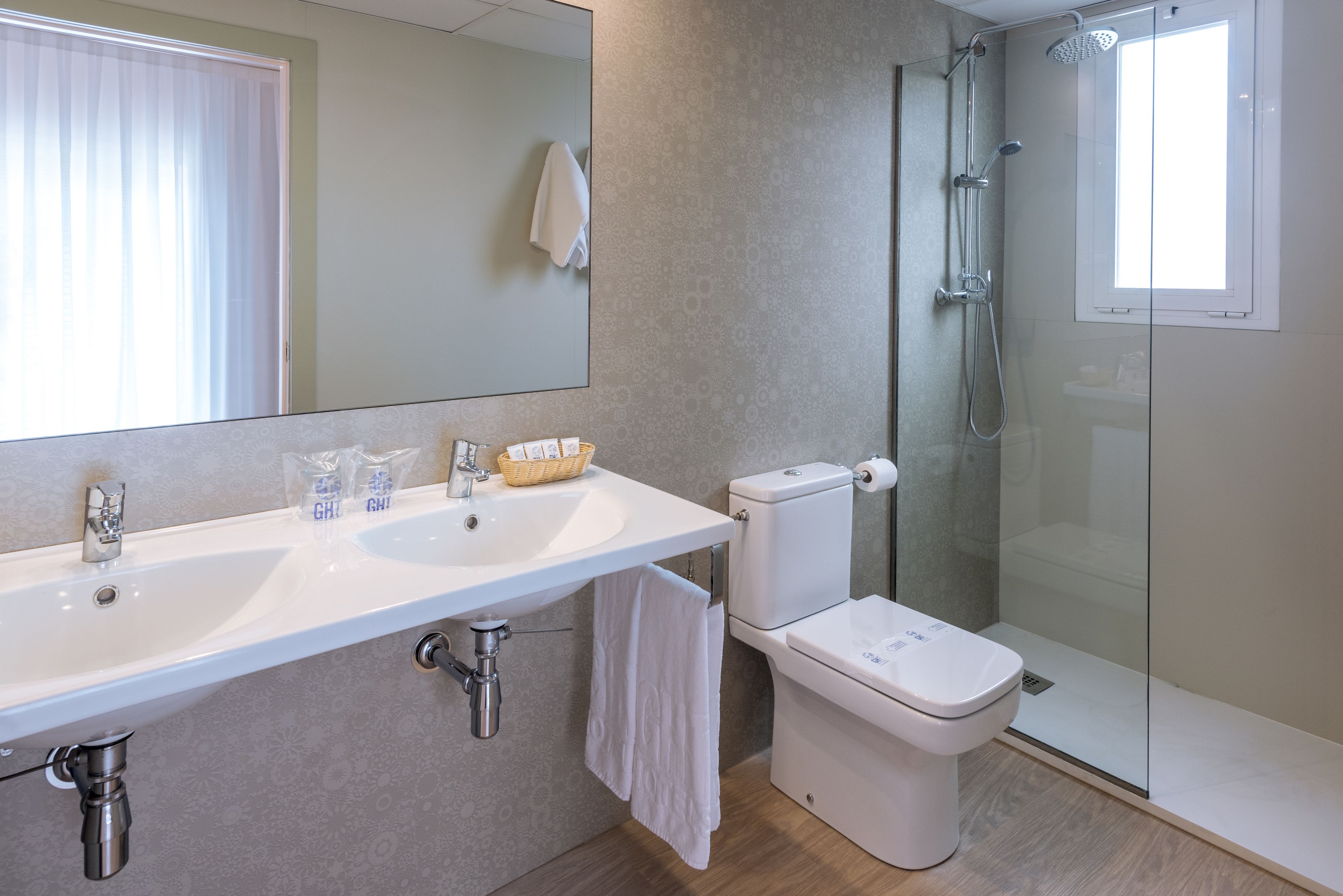 A modern bathroom with a white sink, toilet, and glass shower enclosure.