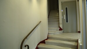 A staircase with a handrail, carpeted steps, and a door at the top. - Hôtel de France (Béziers)