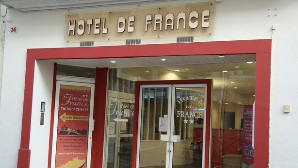 The exterior of Hotel de France with a red and white facade, glass doors, and a sign above the entrance. - Hôtel de France (Béziers)