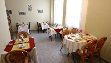 A dining area with multiple tables and chairs, some with red tablecloths.