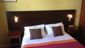 A neatly made bed with white and brown pillows, a wooden headboard, and two bedside tables with lamps.
