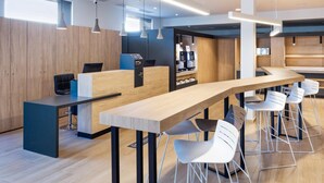 Een moderne kantoorruimte met een lange houten tafel, witte stoelen en hanglampen.