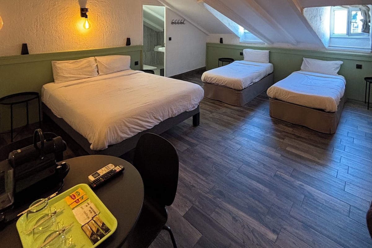 Habitación de hotel con dos camas, un escritorio y una silla. Hay una ventana con vistas al exterior.