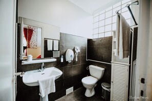 Un baño moderno con un lavamanos blanco, inodoro y espejo.