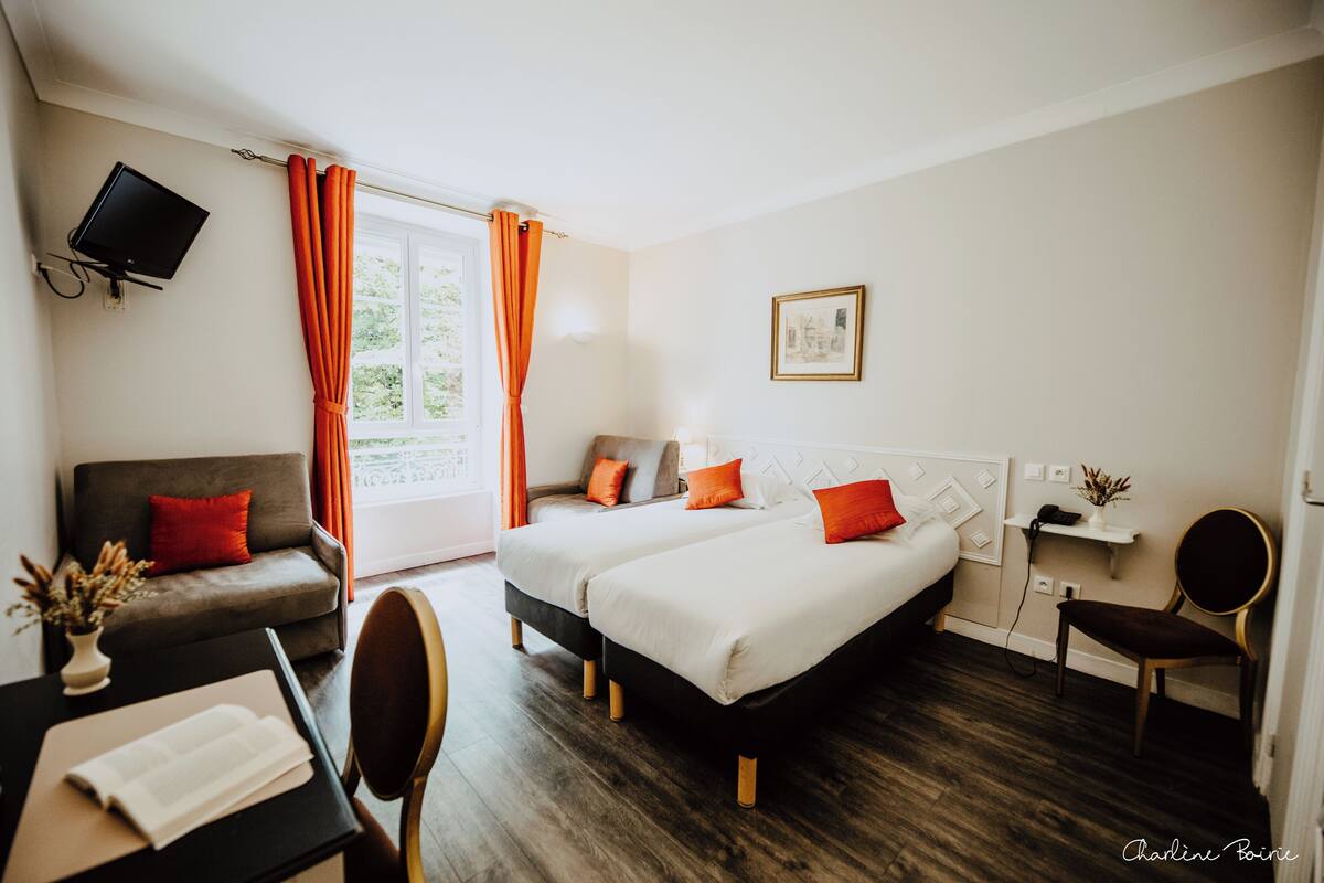 Habitación de hotel con dos camas, un sofá, un televisor y un escritorio con una silla.