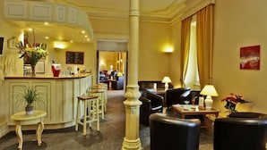 Vestíbulo de hotel con área de bar, asientos y un pilar grande.