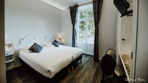 Un dormitorio con dos camas, un escritorio, una silla, un televisor y una ventana con cortinas.