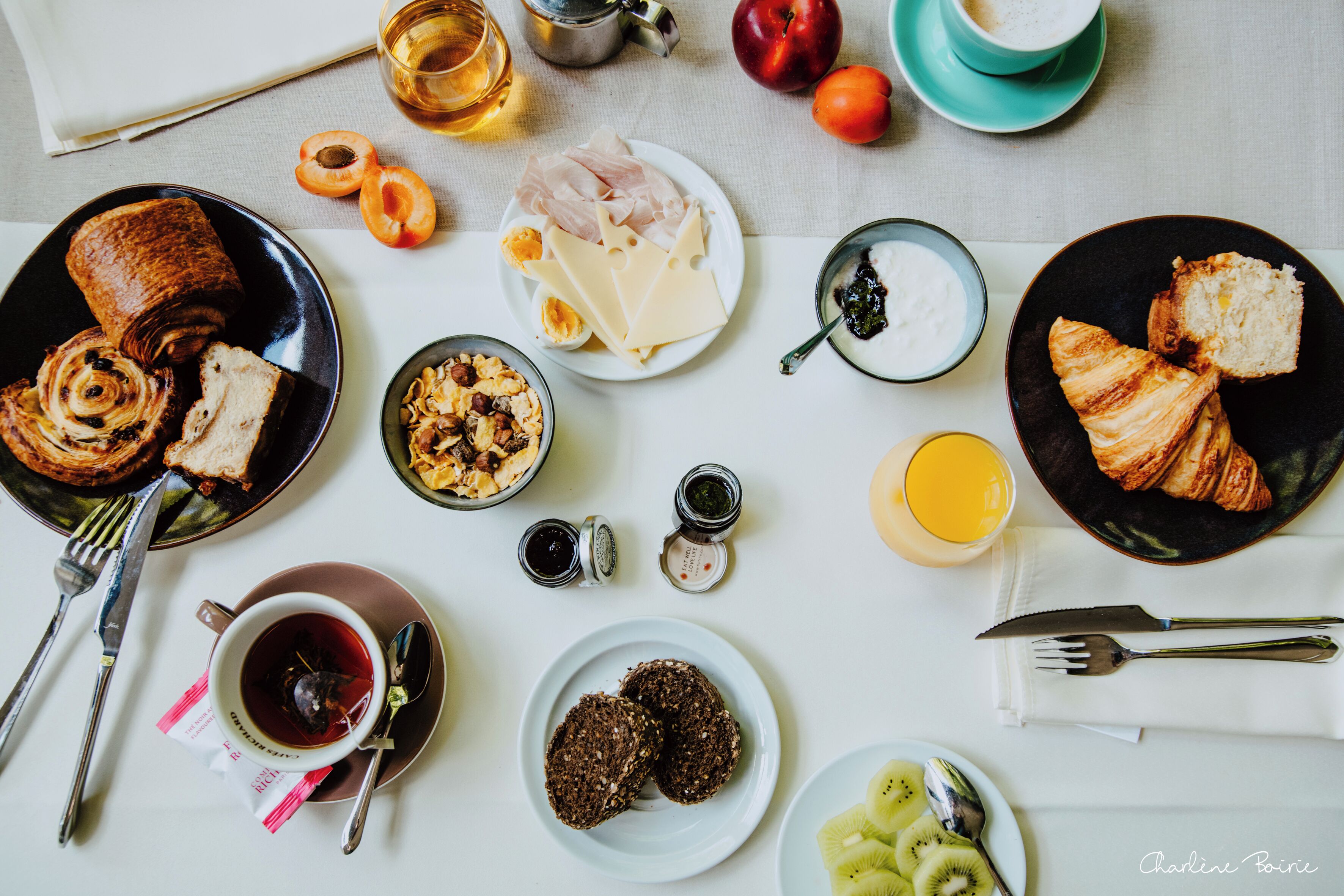 Une table de petit-déjeuner avec divers aliments, ustensiles et condiments.