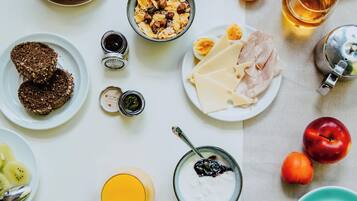 A breakfast table with various food items, utensils, and a teapot.